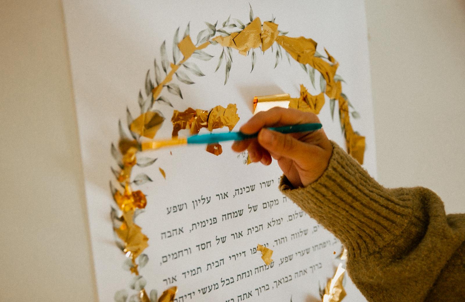 Applying gold leaf to a ketubah by hand